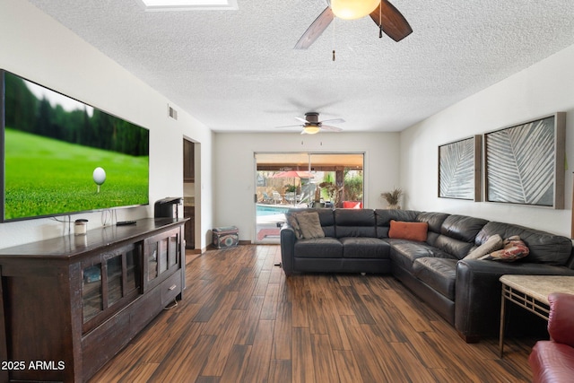 living room with ceiling fan, dark wood-style floors, visible vents, and a textured ceiling