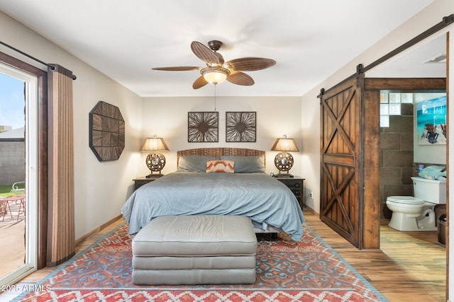 bedroom featuring a barn door, multiple windows, access to exterior, and wood finished floors