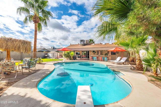 view of swimming pool with a fenced in pool, fence, an outdoor structure, a storage shed, and a patio area