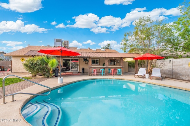 view of pool featuring fence, a fenced in pool, central AC, a patio area, and outdoor dry bar