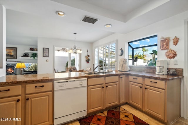 kitchen featuring dishwasher, sink, a notable chandelier, light stone counters, and kitchen peninsula