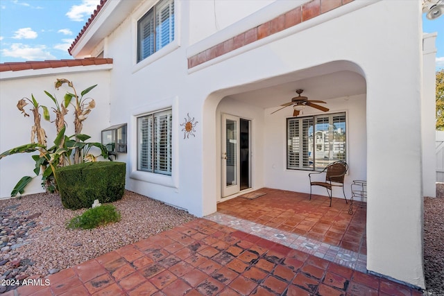 view of exterior entry with a patio area and ceiling fan