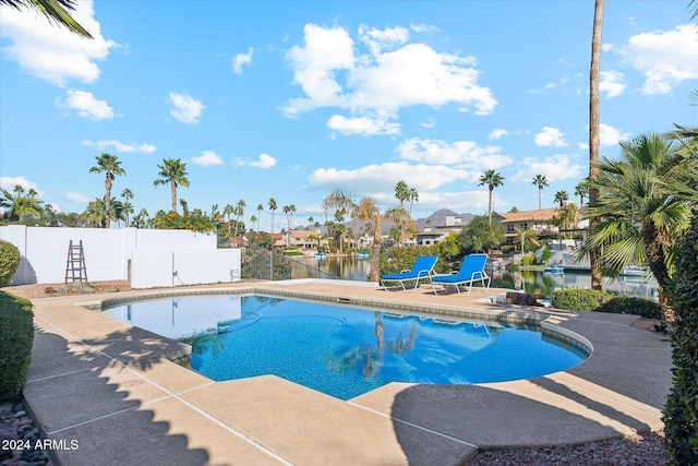 view of swimming pool with a patio area and a water view