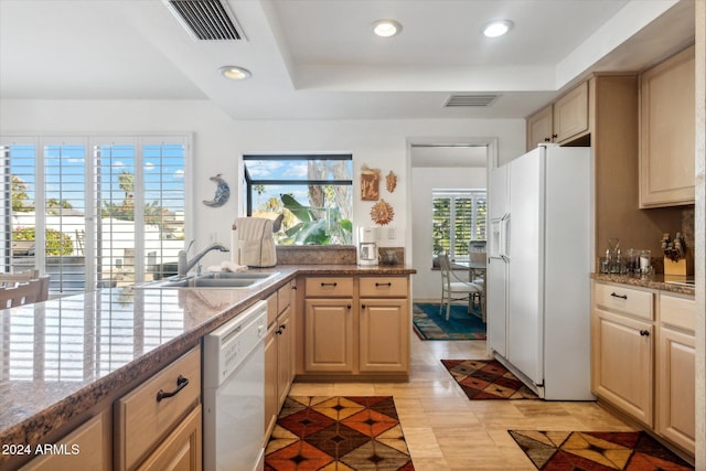 kitchen featuring sink, a raised ceiling, light stone counters, white appliances, and light brown cabinetry