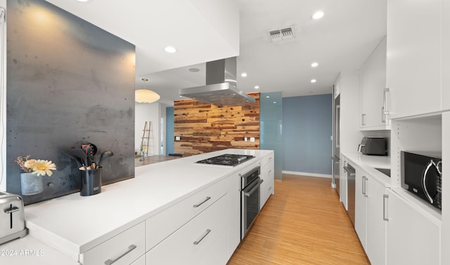 kitchen with light wood-type flooring, stainless steel appliances, island range hood, and white cabinetry