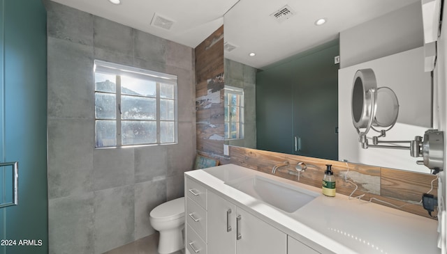 bathroom featuring tile walls, toilet, and vanity