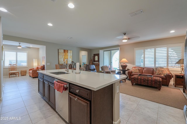 kitchen with sink, light tile patterned flooring, dishwasher, an island with sink, and dark brown cabinets