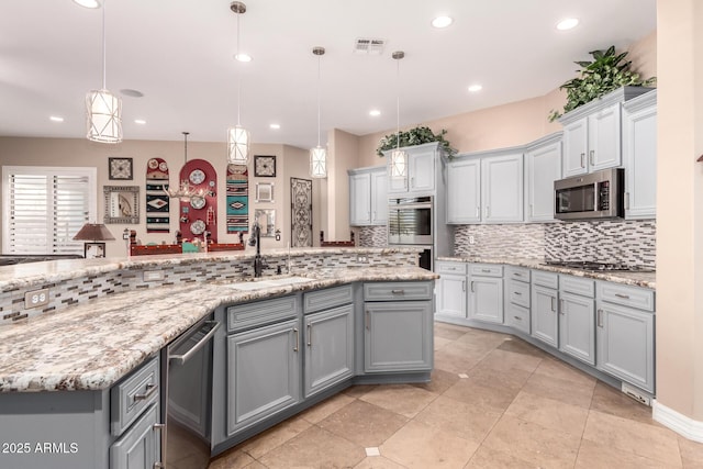 kitchen with appliances with stainless steel finishes, decorative light fixtures, sink, and gray cabinetry