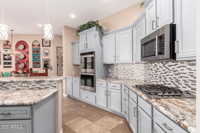 kitchen featuring light stone counters, appliances with stainless steel finishes, decorative light fixtures, and decorative backsplash