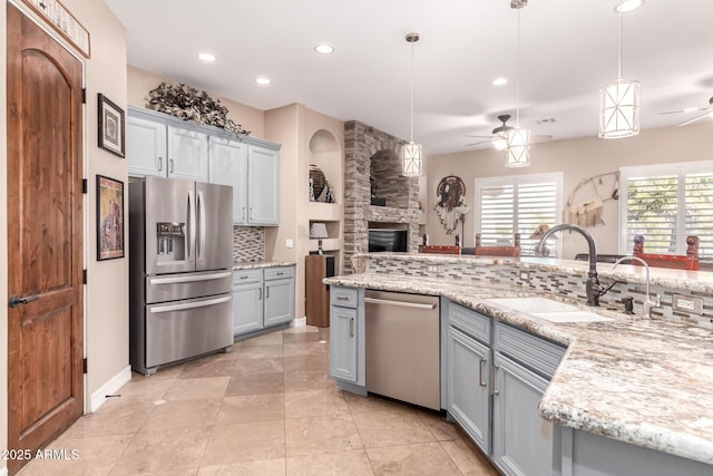 kitchen with decorative light fixtures, gray cabinetry, decorative backsplash, ceiling fan, and stainless steel appliances