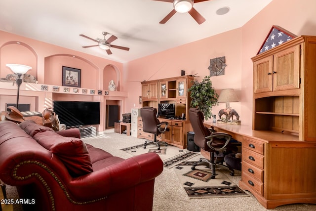 carpeted office with built in desk and ceiling fan