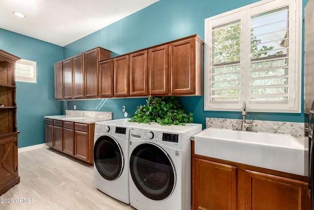 laundry room featuring sink, light hardwood / wood-style flooring, cabinets, and washing machine and clothes dryer