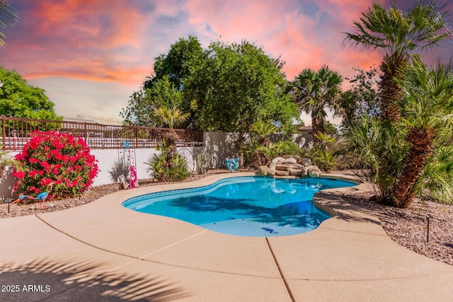 pool at dusk with a patio area