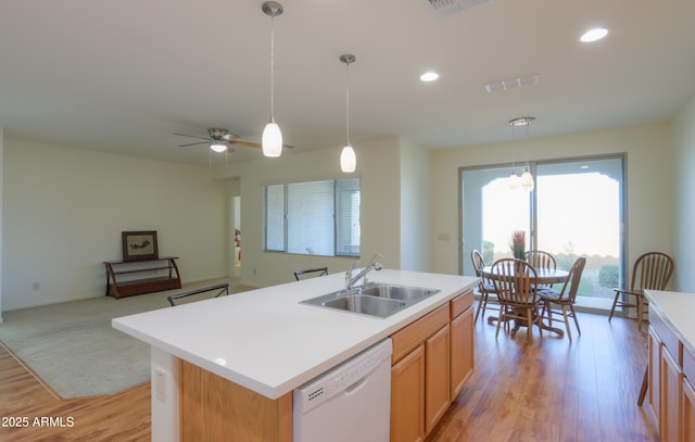 kitchen featuring decorative light fixtures, a kitchen island with sink, sink, and white dishwasher