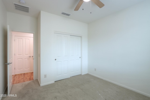 unfurnished bedroom with light carpet, a closet, and ceiling fan