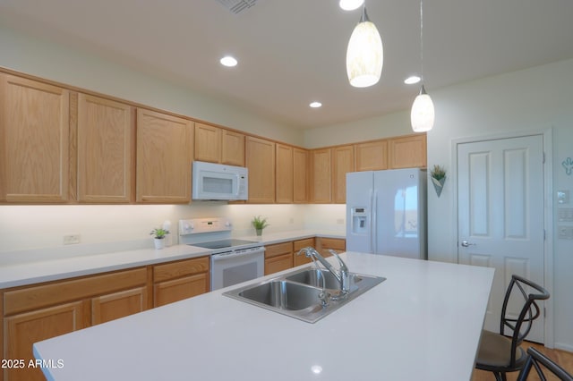 kitchen with decorative light fixtures, sink, white appliances, and an island with sink