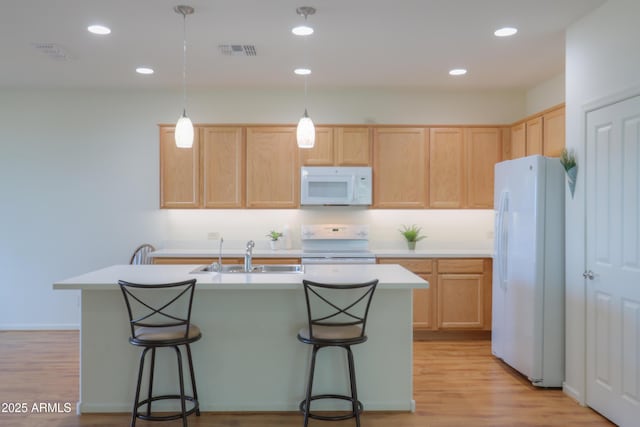 kitchen featuring sink, white appliances, hanging light fixtures, a kitchen island with sink, and light brown cabinets