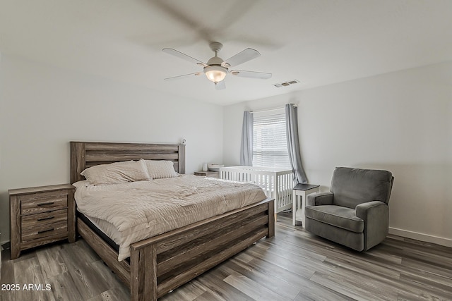 bedroom featuring baseboards, a ceiling fan, wood finished floors, and visible vents