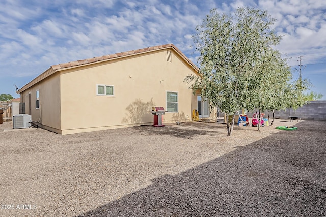 rear view of property featuring stucco siding and cooling unit