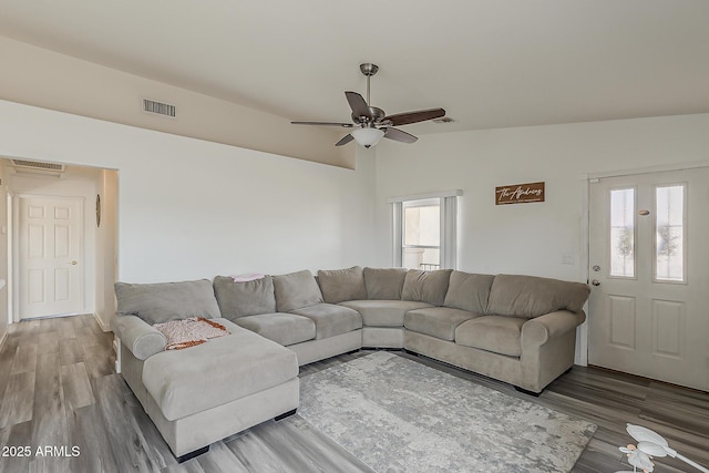 living room with a ceiling fan, visible vents, wood finished floors, and lofted ceiling