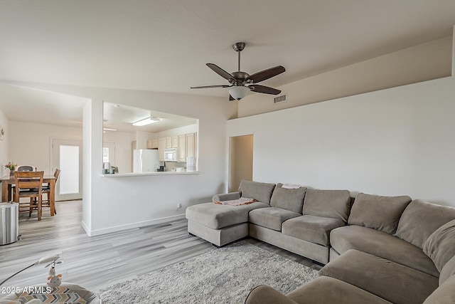 living area with visible vents, baseboards, ceiling fan, and light wood-type flooring