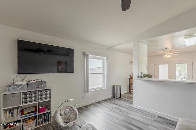 interior space featuring baseboards, a ceiling fan, and light wood-style flooring