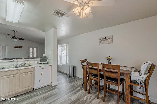 dining room featuring a ceiling fan, visible vents, vaulted ceiling, light wood-type flooring, and baseboards