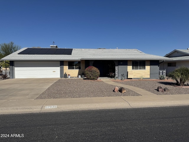 ranch-style house featuring solar panels and a garage