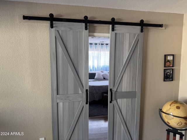 hallway with a barn door and wood-type flooring