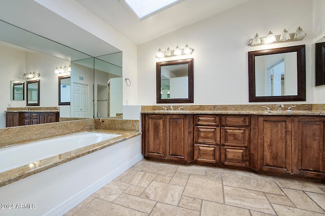 bathroom featuring vanity, lofted ceiling with skylight, and a bathtub