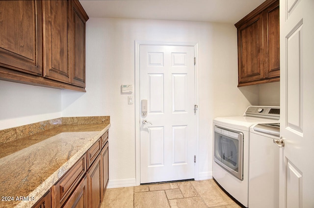 clothes washing area featuring separate washer and dryer and cabinets