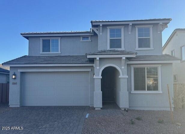 traditional home with decorative driveway, a tile roof, an attached garage, and stucco siding