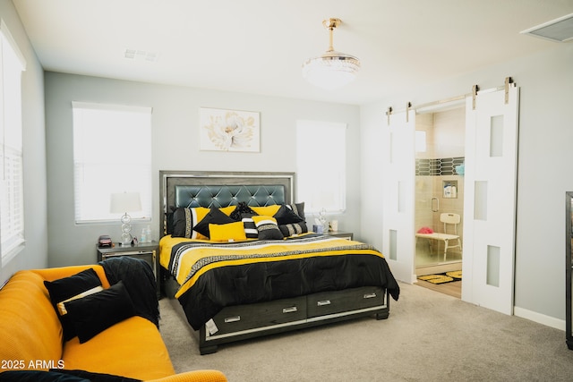 bedroom featuring light colored carpet, connected bathroom, and a barn door