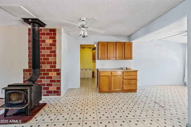 312 W Saddle Ln, Payson, AZ 85541 - kitchen featuring a wood stove, ceiling fan, light countertops, a textured ceiling, and brown cabinets