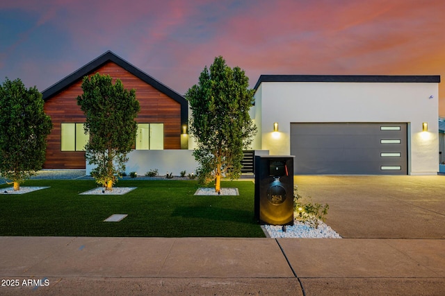 modern home featuring driveway, a yard, an attached garage, and stucco siding