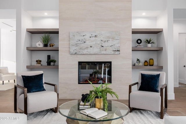 living area featuring built in features, wood finished floors, and a tile fireplace