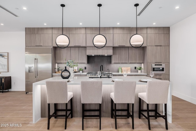 kitchen with hanging light fixtures, modern cabinets, appliances with stainless steel finishes, and light countertops