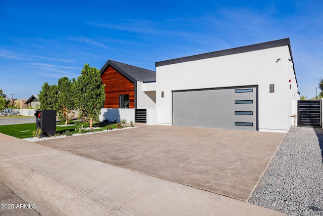 contemporary house featuring concrete driveway, an attached garage, and stucco siding