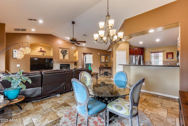 dining space with ceiling fan with notable chandelier and vaulted ceiling