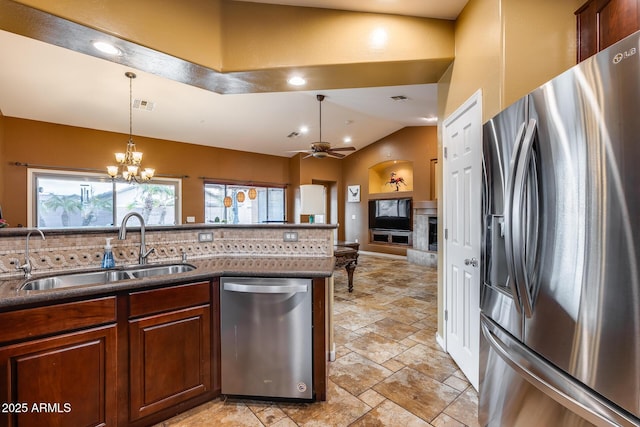 kitchen with lofted ceiling, sink, tasteful backsplash, appliances with stainless steel finishes, and ceiling fan with notable chandelier