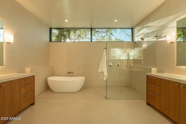 bathroom with a wealth of natural light, a walk in shower, vanity, and tile walls