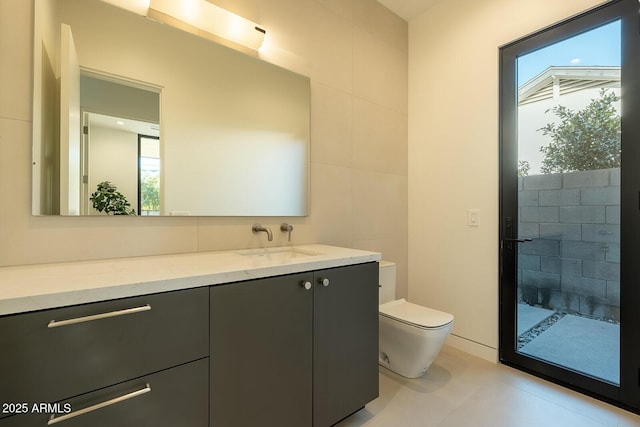 full bathroom featuring a tile shower, toilet, vanity, and tile walls