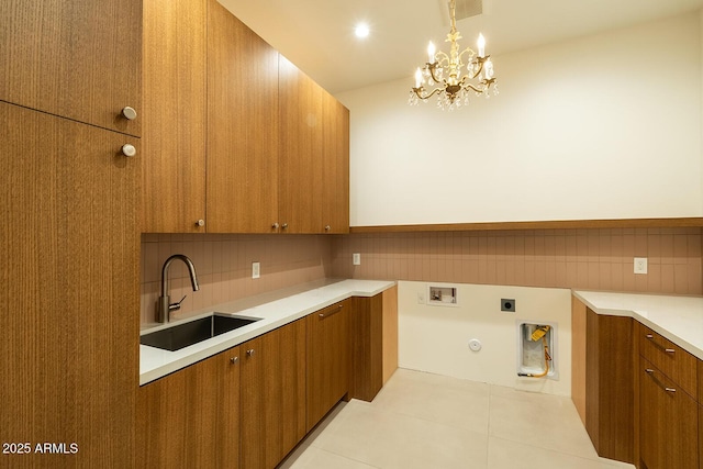 kitchen featuring backsplash, brown cabinets, light countertops, and a sink