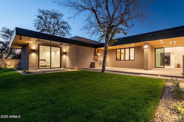 back of property featuring a patio area, a lawn, brick siding, and stucco siding