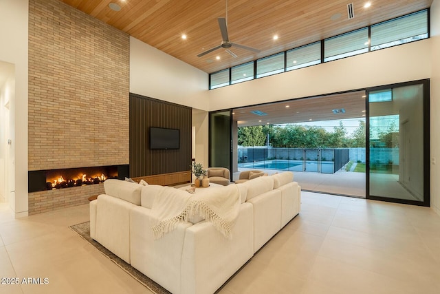 living room with ceiling fan, wood ceiling, recessed lighting, a fireplace, and a high ceiling