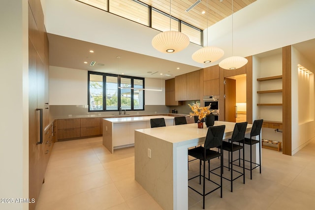 kitchen featuring brown cabinetry, a spacious island, a sink, light countertops, and modern cabinets