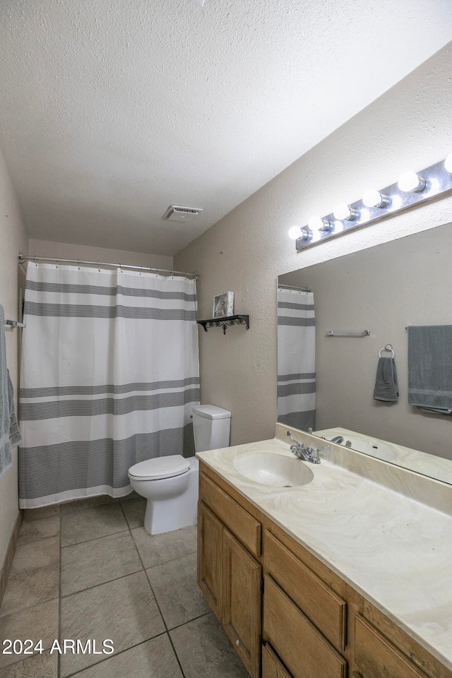 bathroom with vanity, tile patterned floors, curtained shower, toilet, and a textured ceiling