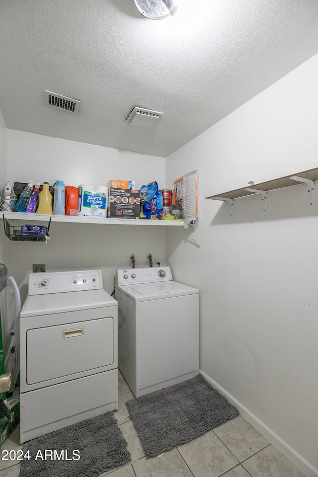 laundry room with washer and clothes dryer, light tile patterned floors, and a textured ceiling