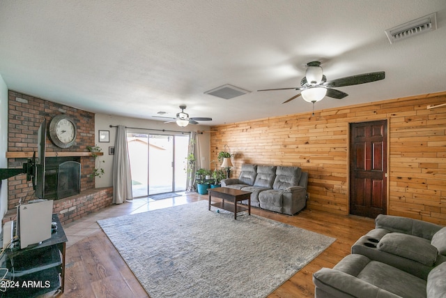 living room featuring a fireplace, wood walls, and light hardwood / wood-style floors