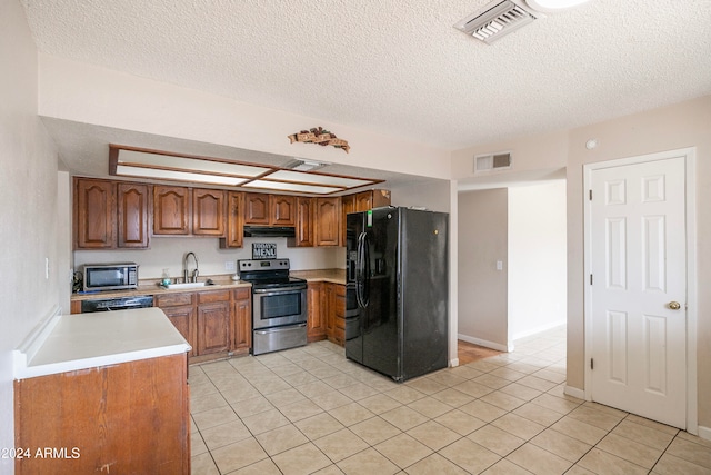 kitchen with stainless steel appliances, light tile patterned flooring, sink, and a textured ceiling